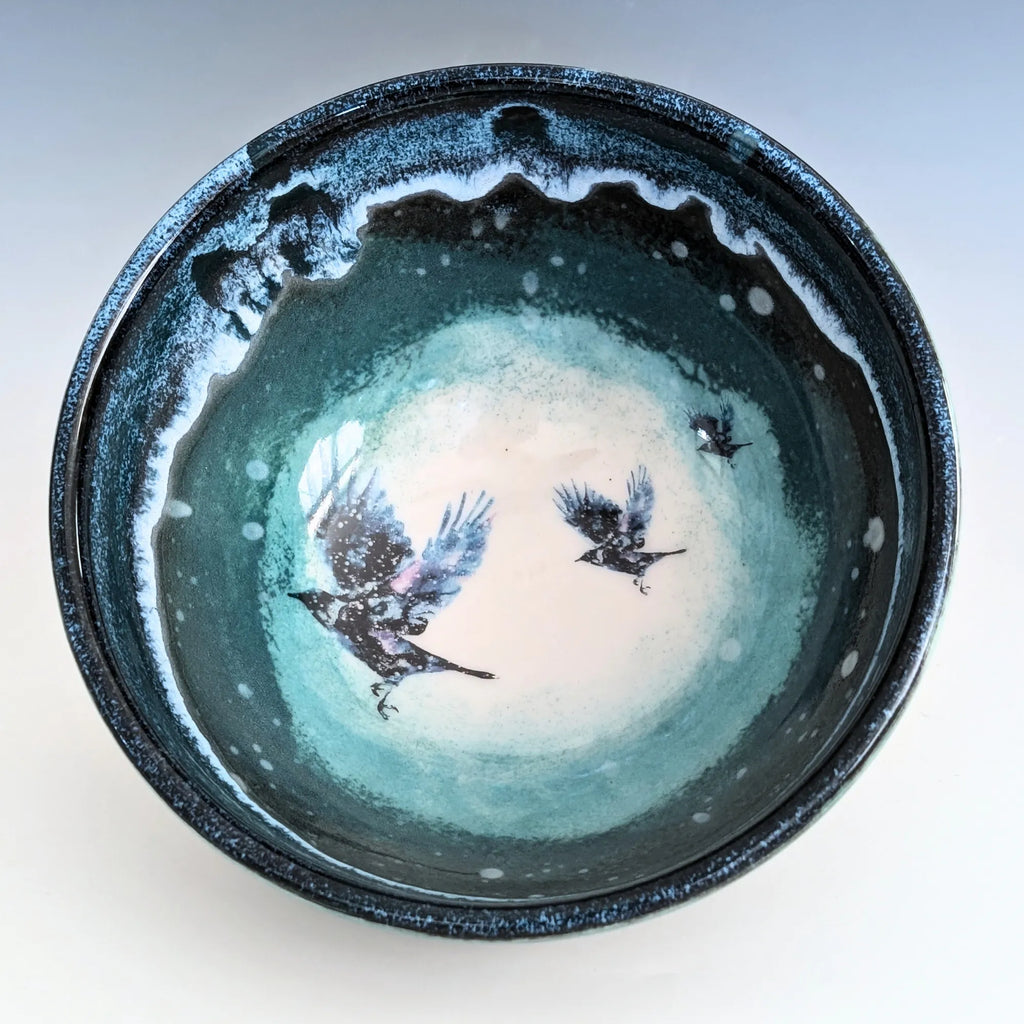 Ceramic bowl with artistic design of birds and a moon on a white background
