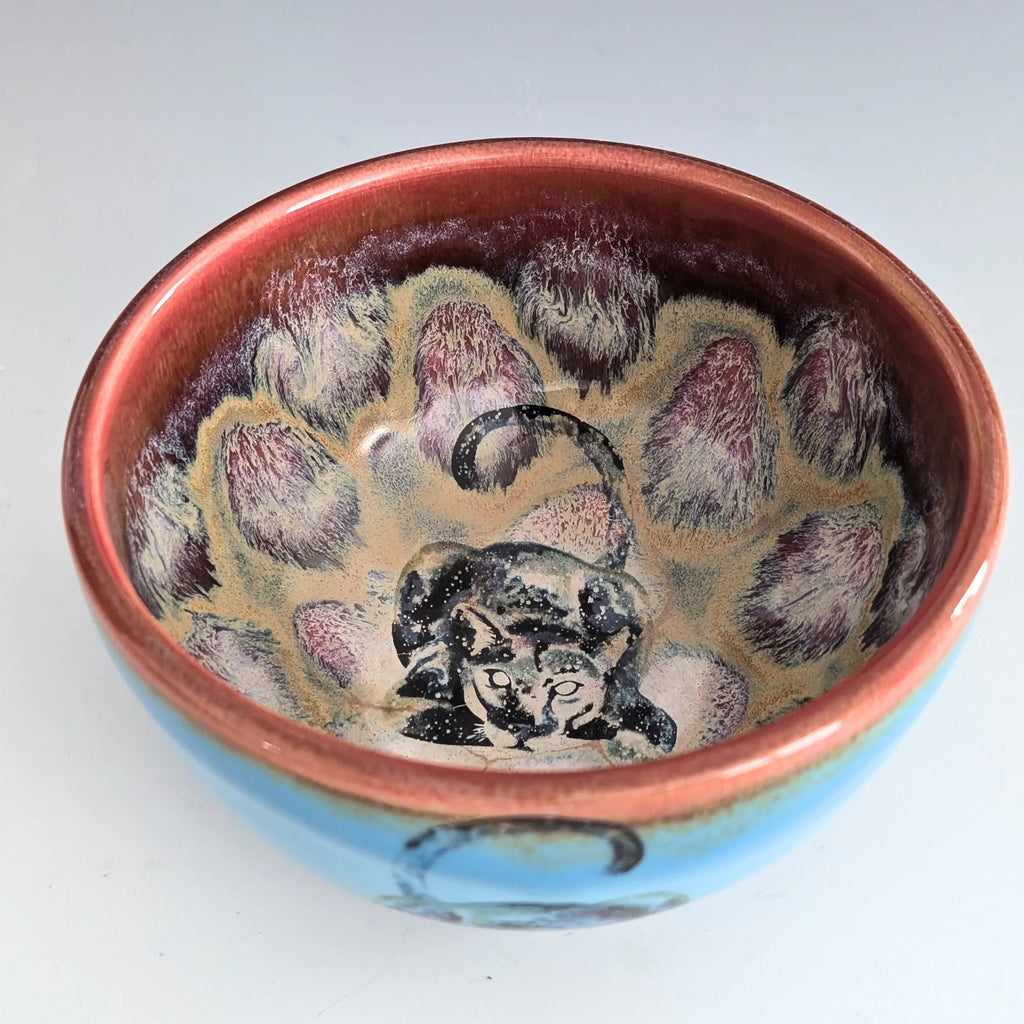 Ceramic bowl with floral design and cat illustration on a white background