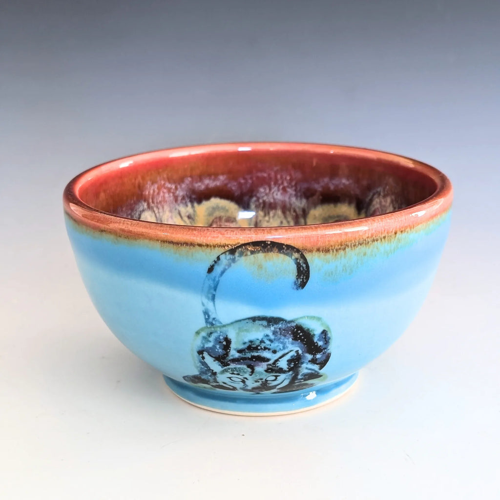 Ceramic bowl with blue body and red rim on a gray background