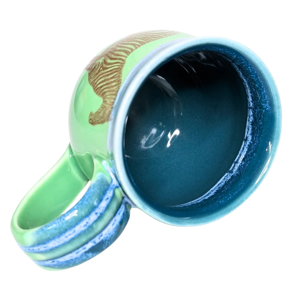 Colorful ceramic mug with a green handle and blue interior on a white background